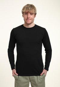 Černé tričko s dlouhým rukávem a kulatým výstřihem, vyrobené z hladkého materiálu. Těsně přiléhá k tělu s jednoduchým, minimalistickým designem.