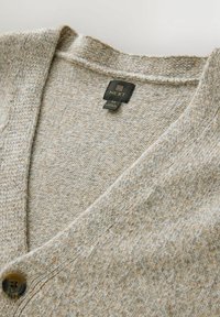 Beige knitted cardigan featuring a v-neck, textured fabric, and a dark button. Label shows brand "NEXT" and size "M."