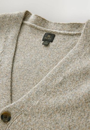 Beige strikket cardigan med v-hals, struktureret stof og en mørk knap. Mærket viser mærket "NEXT" og størrelse "M."