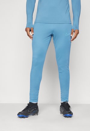 Blue athletic pants with a smooth texture and fitted design, featuring a subtle Nike logo in light blue. Worn with black cleats.