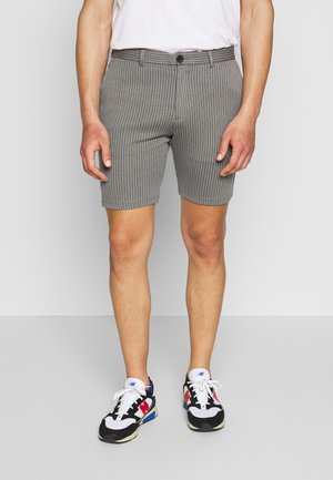 Grijs gestreepte korte broek met een rechte pasvorm, voorzien van een knoopsluiting en riemlussen. Draagt zwarte en witte sneakers.