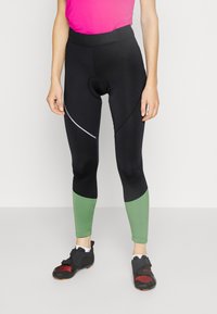 Leggings de ciclismo negras con acentos verdes en el dobladillo, con una cintura alta y detalles reflectantes en los lados.