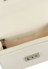 Bolso de mano de cuero blanco texturizado con un cierre de hardware plateado y un bolsillo interior con cremallera. Diseño conciso con un forro suave.