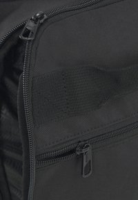 Black fabric backpack featuring a textured surface, multiple zippers, and a strap detail. Focus on functionality and durability in design.