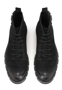 Botas de tobillo de ante negro con cordones en la parte delantera, superficie texturizada y cierre de cremallera lateral. Suelas de goma resistentes con punta redonda y un detalle mínimo.