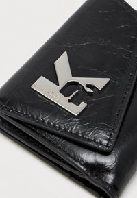 Carteira preta de couro com uma textura enrugada, apresentando um destacado hardware de logotipo prateado e um design dobrado.