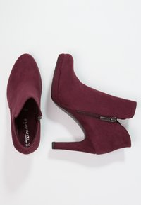 Burgundy mokasii nilkkurit, joissa on teräväkärkinen muotoilu, 10 cm korkea korko ja sivuvetoketjuyksityiskohta helppoa pukeutumista varten. Sileä pinta ja tyylikäs muotoilu.