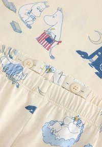 Najważniejsze cechy zestawu: kremowa tkanina z niebieskimi postaciami Muminków. Koszula ma okrągły dekolt; spodnie mają elastyczną talię i ozdobny guzik.