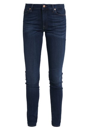 Dark blue denim jeans with a slim fit, featuring a button closure, belt loops, and classic 5-pocket styling. Subtle stitching accents.