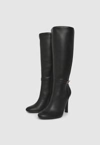 Stivali neri in pelle alti fino al ginocchio con tacco affusolato, cerniera laterale e sottile accento dorato alla caviglia. Texture liscia e design aderente.