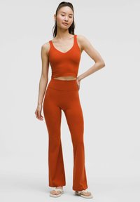 Rode sportieve crop top en aansluitende wijde leggings van rekbare stof, met een V-hals ontwerp en een gladde textuur.