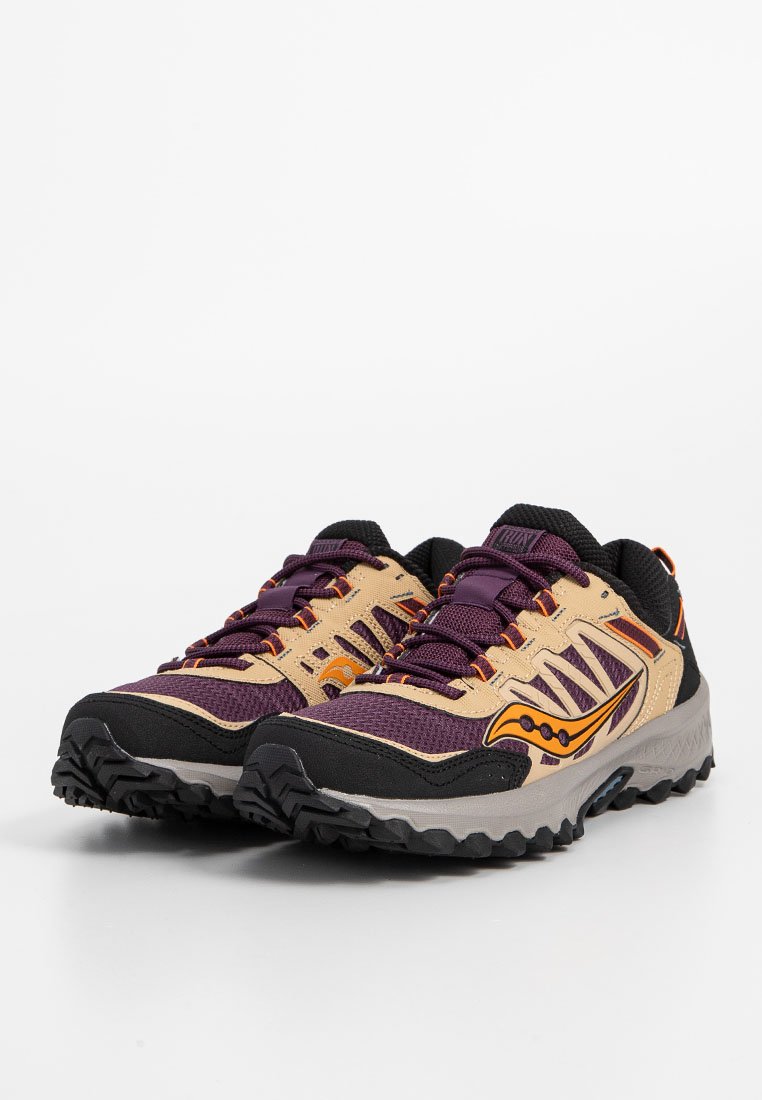 Scarpe da trail running in beige, viola e nero. Presentano una tomaia testurizzata, una punta rinforzata e una suola robusta per la trazione.