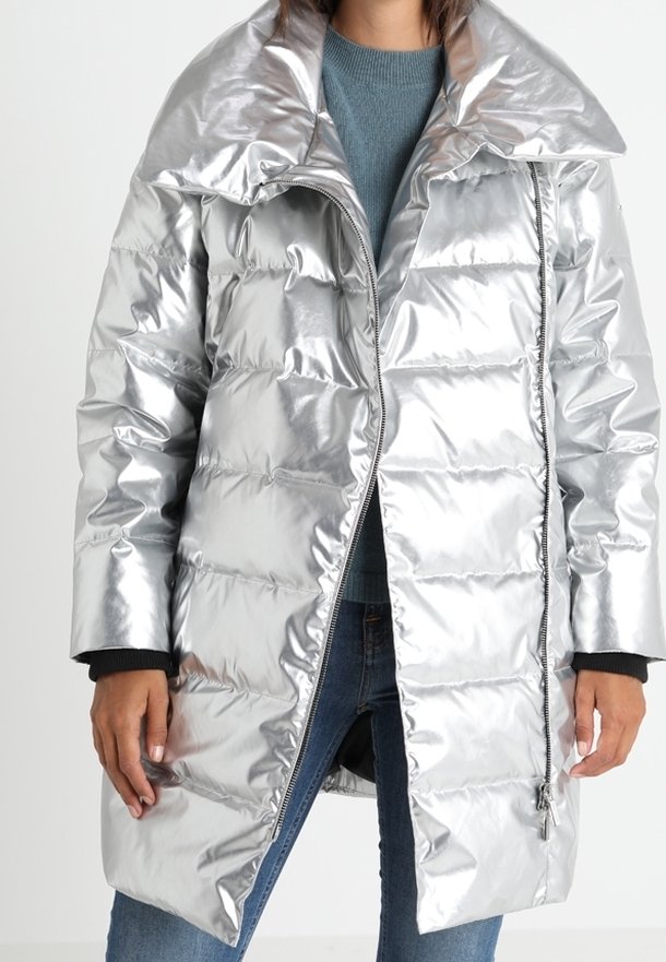 Srebrna, metaliczna kurtka puchowa ze dużym kołnierzem, zapinana na zamek z przodu, pikowana. Posiada długie rękawy i długość do połowy uda.