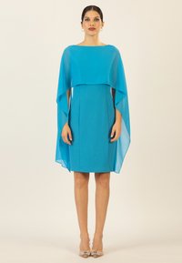 Ein leuchtend blaues Kleid mit einem fließenden Überwurf, in Oberschenkelhöhe, mit einer figurbetonten Silhouette und glatter Textur.