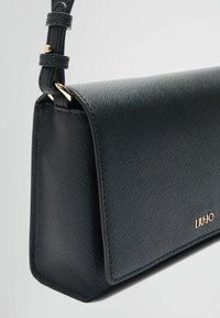 Borsa a mano in pelle nera con finitura testurizzata, dettagli in metallo dorato e design strutturato. Include una tracolla regolabile per maggiore versatilità.
