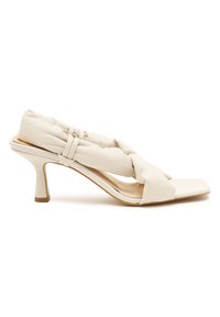 Witte hakken sandaal met een gedraaid, gevoerd leren bovenwerk, open teen en een slanke stiletto hak met een contrasterende bruine accent.
