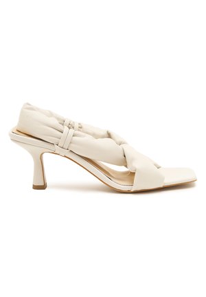 Witte hakken sandaal met een gedraaid, gevoerd leren bovenwerk, open teen en een slanke stiletto hak met een contrasterende bruine accent.