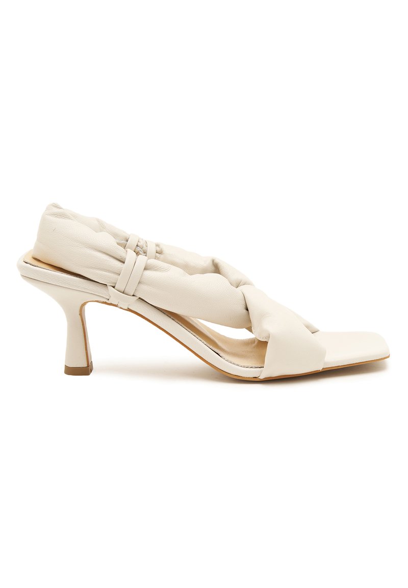 Witte hakken sandaal met een gedraaid, gevoerd leren bovenwerk, open teen en een slanke stiletto hak met een contrasterende bruine accent.