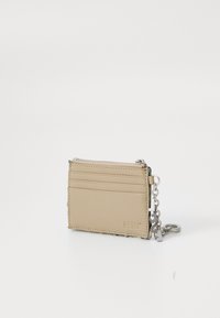 Beige cardholder made of synthetic material, featuring a zip pocket, three card slots, silver chain hardware, and embossed logo detail.