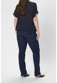 Navy blouse with loose fit and short sleeves paired with dark blue denim jeans. Black pointed toe heels complete the look.