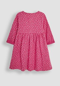 Roze katoenen jurk met witte stippen, ronde hals, lange mouwen en een uitlopende rok. Heeft gathered details bij de taille.