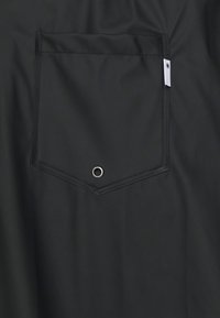 Svart tygficka med en diamantform, med en silverfärgad ögla i botten. Enkel design med synliga sömmar och etikett.