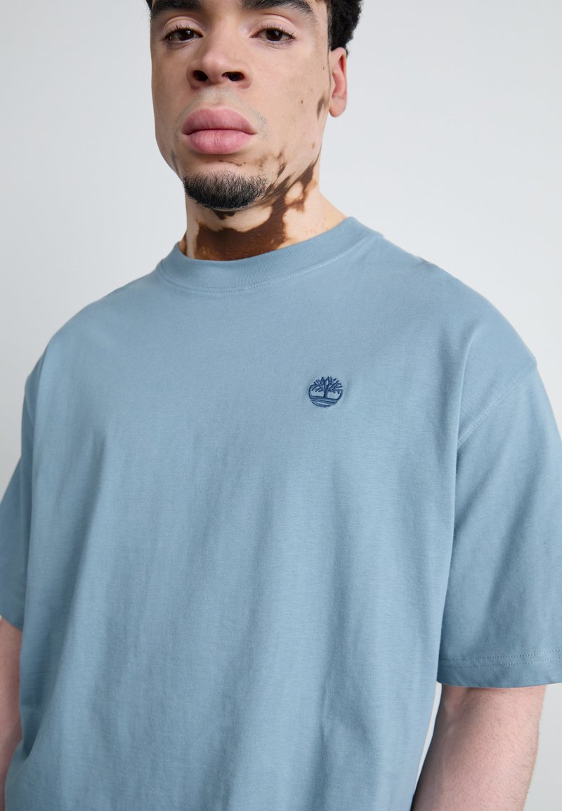 T-shirt en coton bleu clair à manches courtes et col rond, ornée d'un logo brodé sur la partie gauche de la poitrine.