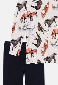 Horse-patterned top in cream with long sleeves paired with solid navy blue trousers, featuring a soft texture and relaxed fit.
