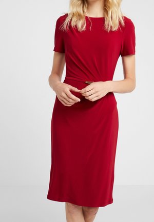 Rode jurk tot op de knie met korte mouwen, een aansluitende pasvorm en een gedraaide voorkant. Voorzien van een metalen gesp in de taille.