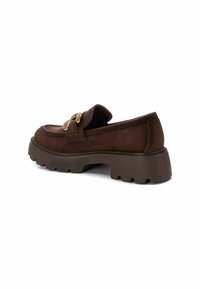 Mocasines de ante marrón con una suela de goma gruesa y texturizada, y un adornado de hardware dorado en la parte delantera. Diseño de punta redonda.