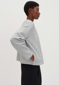 Grijze sweatshirt met een gestructureerd oppervlak, ronde halslijn en lange mouwen. Voorzien van zijzakken en een relaxed fit ontwerp.