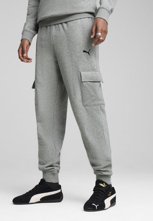 Grå cargo-joggers lavet af blødt stof, med sidelommer og et broderet logo på venstre lår. Kombineret med sorte sneakers.
