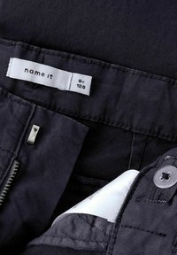 Črne bombažne hlače z gladko teksturo, z zadrgo, gumbom za zapiranje in tkano oznako z napisom "name it" v belem.