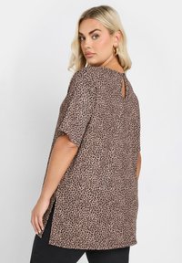 Leopardmönstrad topp i beige och brunt, med rund halsringning, korta ärmar och en nyckelhålsdetalj på baksidan. Finns i en lös passform.