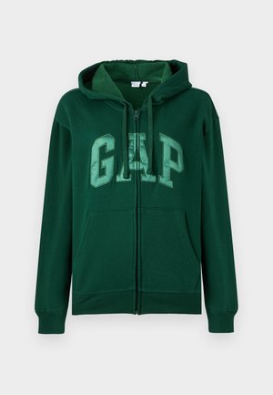 Green zip-up hoodie made of soft fabric. Features a large GAP logo in a lighter green. Includes a hood and two front pockets.