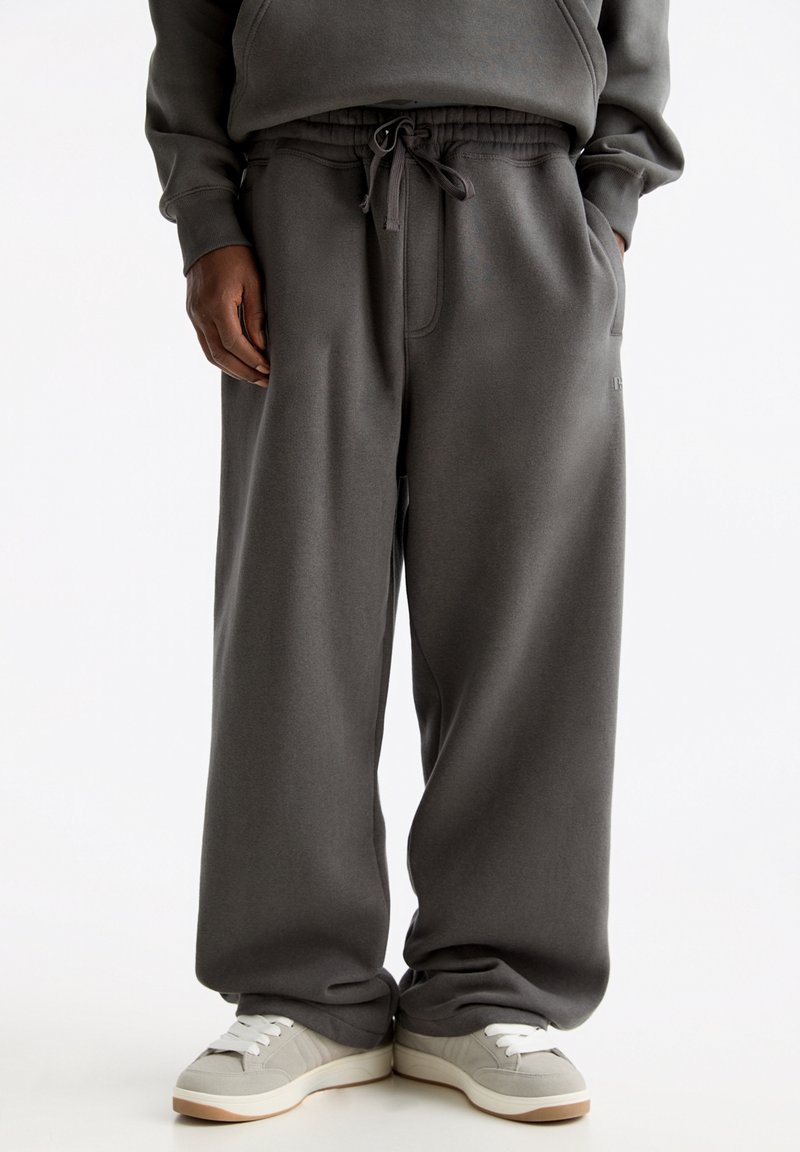 Grå, löst sittande joggingbyxor med elastisk midja, dragsko och sidofickor. Mjuk bomullsmix, enkel design.