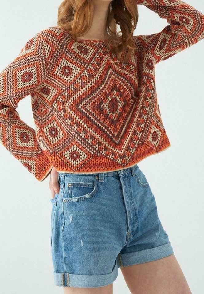 Strickpullover in Orange und Creme mit geometrischen Mustern; kombiniert mit hellblauen Jeansshorts mit umgeschlagenen Säumen und verwaschenen Details.