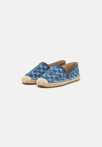Blå denim espadrillos med en vävd jutesula, med en rundad tå och en slät svart kant längs kanten. Diskret cirkulärt mönster.