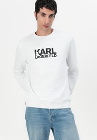 Sudadera blanca con el logo negro "KARL LAGERFELD". Mangas largas, cuello redondo, tela suave, corte relajado y puños y dobladillo acanalados.