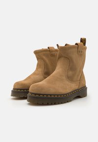 Suède enkellaarsjes in tan met een gladde textuur, versterkte stiksels, een heel lus en een dikke rubberen zool met gele accenten.