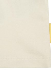 Baumwollkleidung in Off-White, mit einer glatten Textur und einem genähten Saum. Ein leuchtend gelbes Akzentetikett ist an der Seite sichtbar.