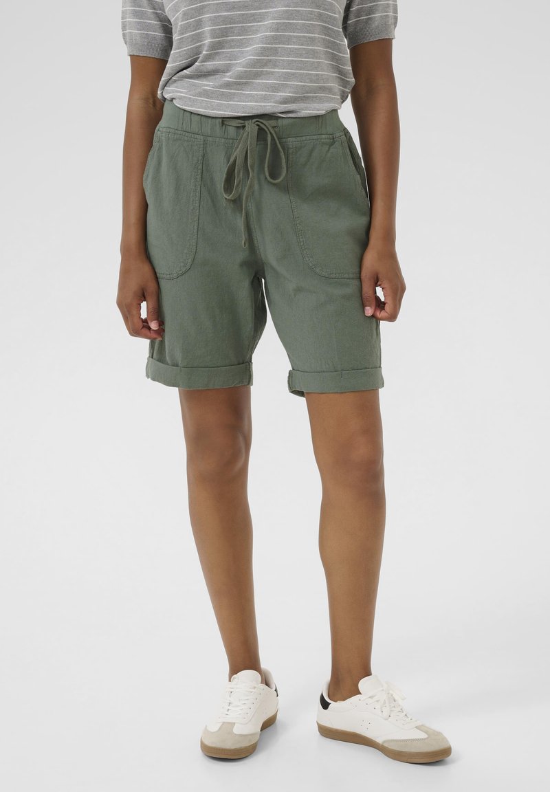 Shorts verts avec une taille élastique et un cordon de serrage, dotés de deux grandes poches avant et de ourlets roulés, fabriqués dans un tissu léger.