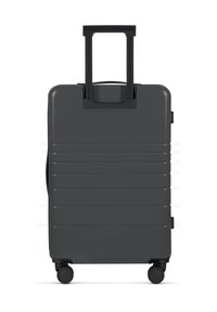Schwarzer Hartschalenkoffer mit strukturierter Oberfläche, zwei Inline-Rädern und einem ausziehbaren Griff. Verfügt über horizontale Rillen für besseren Halt.