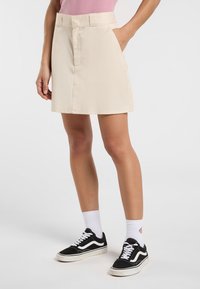 Beige bomullsshort med en åtsittande midja, platt framfickor och rak passform. Matchad med svarta Vans-sneakers och vita ankelsockar.