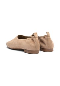 Beige zamšveida kurpes ar zemu papēdi, ar noapaļotu purngalu un dekoratīvu lentu aizmugurē. Gluda tekstūra.