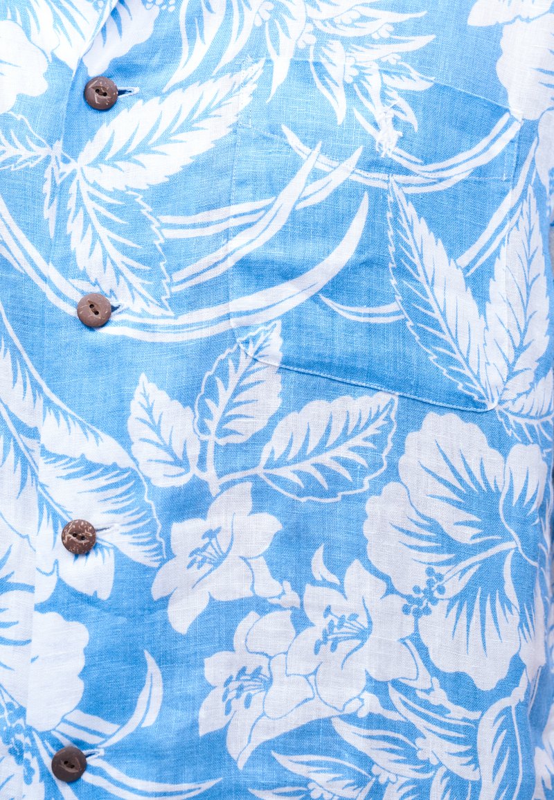 Lichtblauwe stof met witte tropische bloemen- en bladpatronen, met bruine knopen langs het verticale midden.