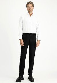 Czarne proste spodnie o gładkiej teksturze, zestawione z białą koszulą z guzikami. Posiadają kieszenie z przodu oraz zapięcie na guzik.
