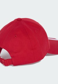 Casquette de baseball rouge avec sangle réglable et œillets de ventilation, posée sur une surface gris clair.