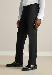 Black dress pants with a straight fit, featuring a smooth texture and subtle satin side stripe, paired with polished black shoes.