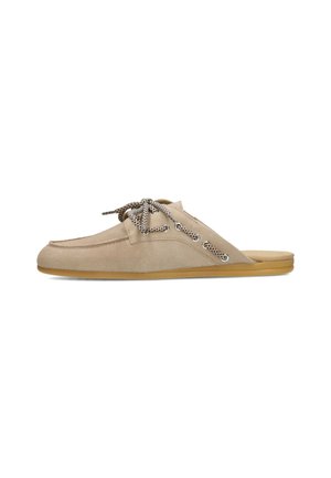 Mocassin beige en daim à enfiler avec des lacets blancs et noirs à motif, des œillets argentés et une semelle plate en caoutchouc marron clair.